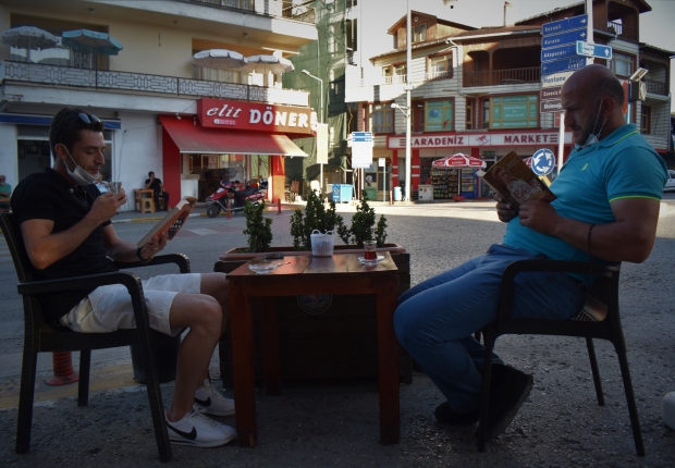 رجلان يقرآن الكتب على طاولة خارج مقهى في دوزجي شمال تركيا-الأناضول