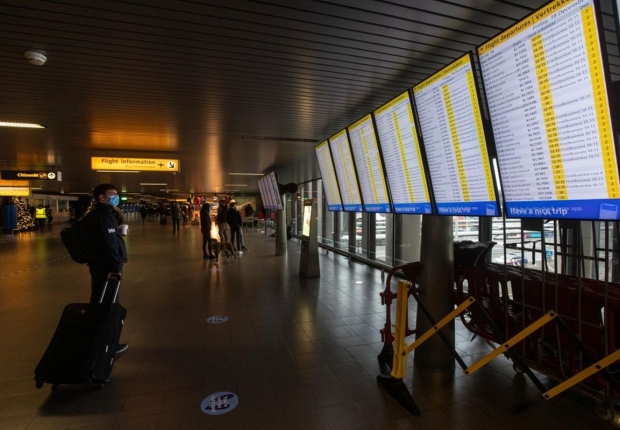 مسافر يرتدي قناع وجه يتحقق من موعد إقلاع الرحلة في مطار شيفول، أمستردام-AP