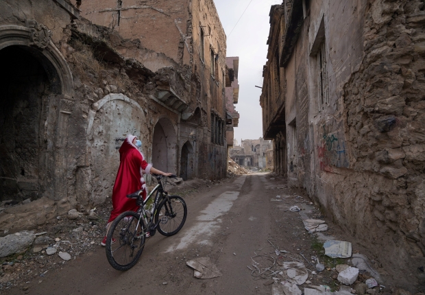 عراقية ترتدي زي بابا نويل وهي تمشي مع دراجتها في مدينة الموصل- 18 ديسمبر، 2020 -رويترز