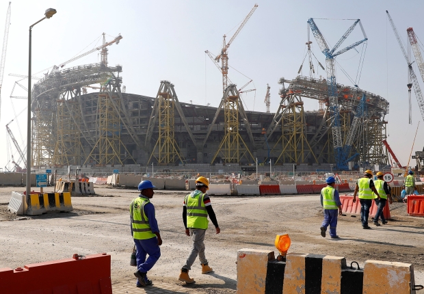 عمال يسيرون نحو موقع بناء ملعب لوسيل الذي سيتم بناؤه لاستضافة مباريات مونديال 2022