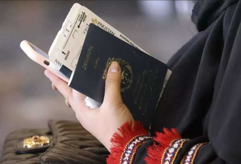 امرأة تحمل جواز سفرها قبل ركوب طائرة تابعة للخطوط الجوية الباكستانية