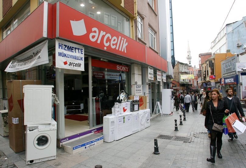 أشخاص يمشون أمام متجر يبيع غسالات وثلاجات في اسطنبول