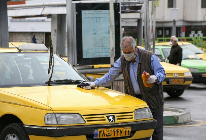 سائق سيارة أجرة يقوم بتنظيف سيارته في محطة نقل غرب طهران -فرانس برس