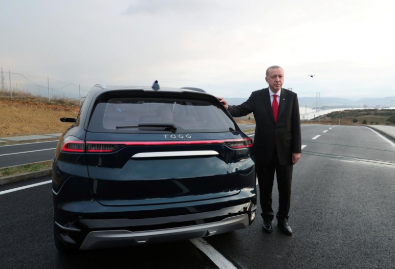 أردوغان يقف بجوار سيارة كهربائية تركية-رويترز