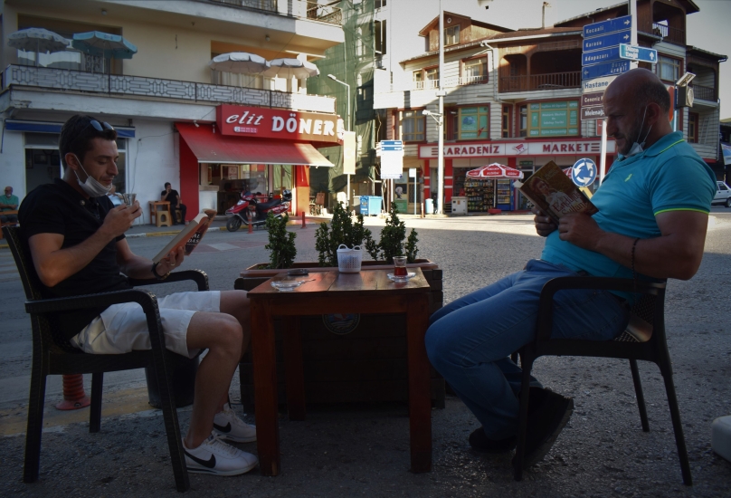 رجلان يقرآن الكتب على طاولة خارج مقهى في دوزجي شمال تركيا-الأناضول