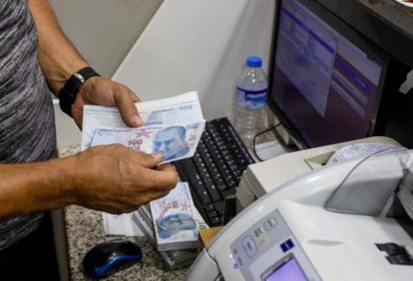 مصرفي يقوم بعد أوراق نقدية بالليرة التركية لأحد العملاء في إسطنبول-أرشيفية