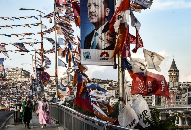 سيدات يسرن على جسر أمام لافتات الحملة الانتخابية قبل الانتخابات العامة في في إسطنبول، 18 يونيو ، 2018.