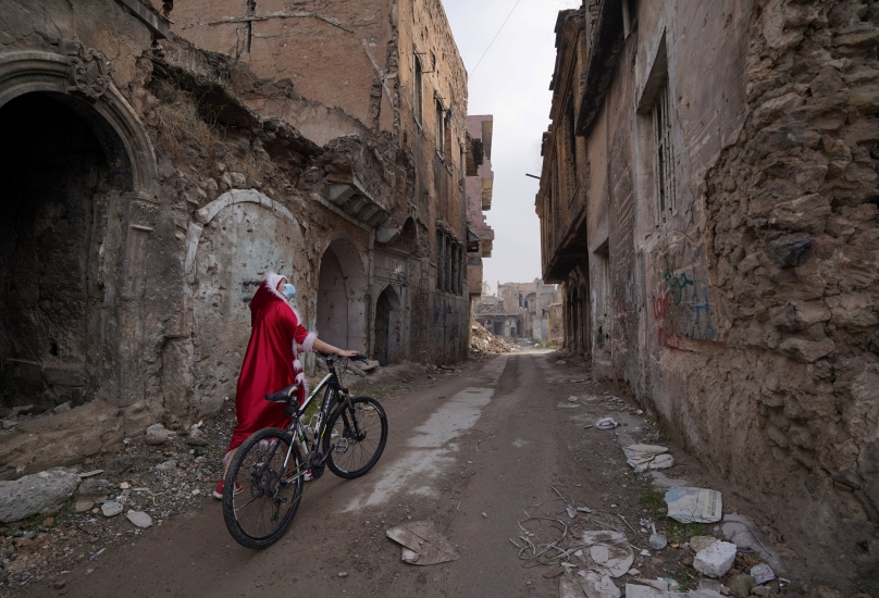 عراقية ترتدي زي بابا نويل وهي تمشي مع دراجتها في مدينة الموصل- 18 ديسمبر، 2020 -رويترز