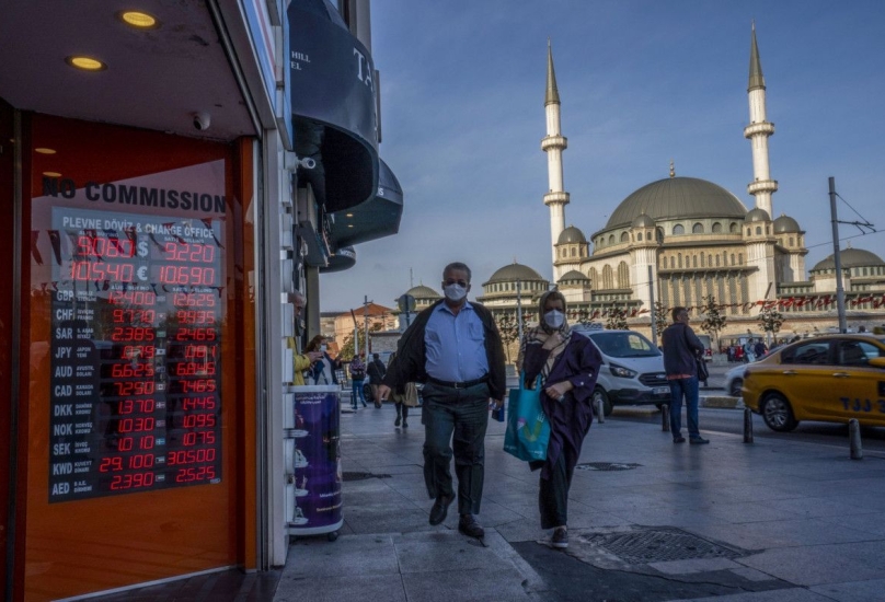 رجل وامرأة يعبران من أمام لوحة إلكترونية لأسعار صرف العملات في إسطنبول