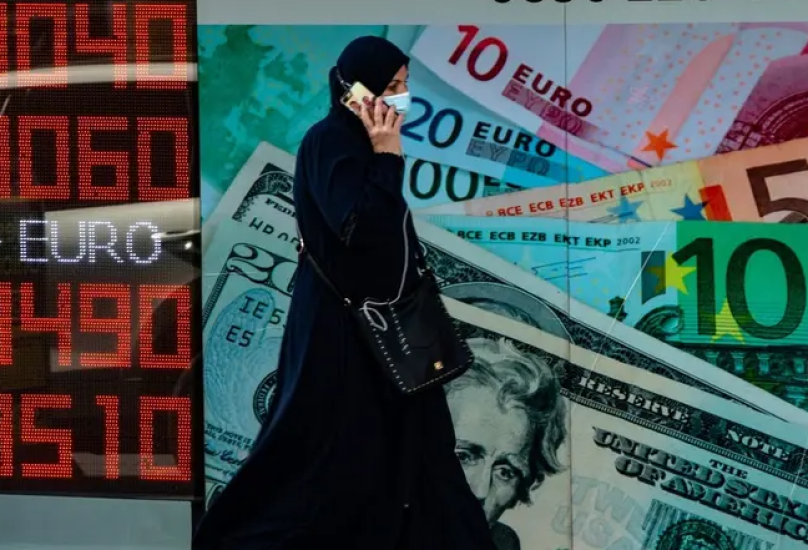 امرأة تمر عبر شاشة معلومات تعرض الأسعار أمام مكتب صرافة في اسطنبول-فرانس برس