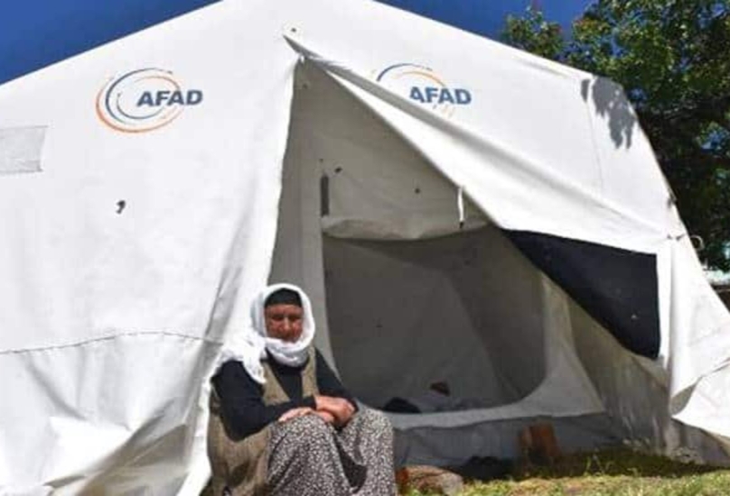 حاجة تركية تجلس أمام خيمة وفرتها إدارة الكواث والطوارئ-صورة أرشيفية